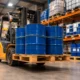 Forklift lifting chemical drums on a CP3 pallet inside an industrial warehouse